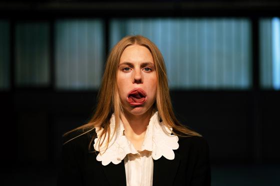 A surreal portrait of a woman with her tongue folded multiple times in an unnatural manner, adding an unsettling yet mesmerizing effect to her neutral facial expression.