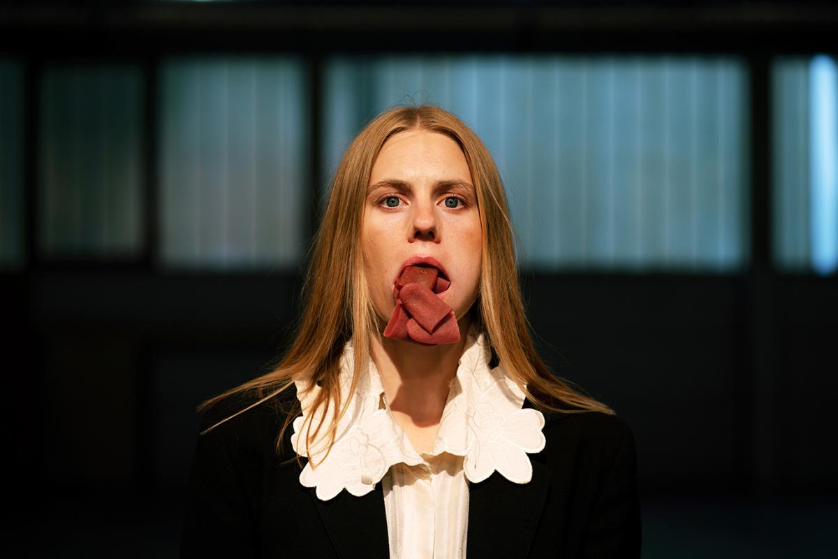 A surreal portrait of a woman with her tongue folded multiple times in an unnatural manner, adding an unsettling yet mesmerizing effect to her neutral facial expression.