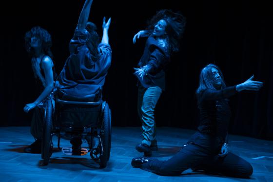 Four white bodies dance in the darkness. Night-blue shimmers on their skin, shoulders, forearms, wheels, legs. Arms stretched out, hands grasping, fingers spread. Wild hair swirls, falls into faces. A demanding smile, a joyful laugh, a concentrated gaze.