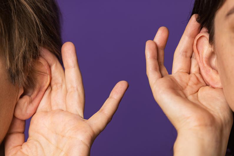 Two people cupping their ears with their hands, as if trying to hear something better, against a purple background.
