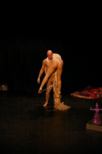 A performer carries another over their shoulder; their long, blonde braid reaches the floor.