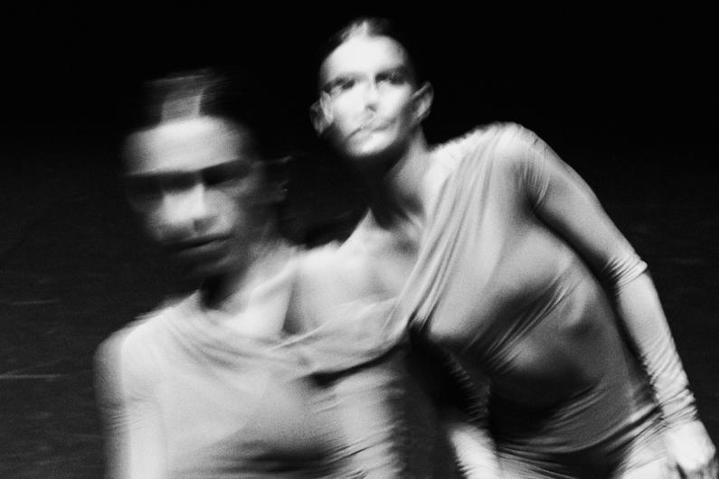 Eine Schwarz-Weiß-Aufnahme zweier Frauen in Bewegung. Die verschwommenen Konturen verleihen dem Bild eine dynamische, fast gespenstische Wirkung.